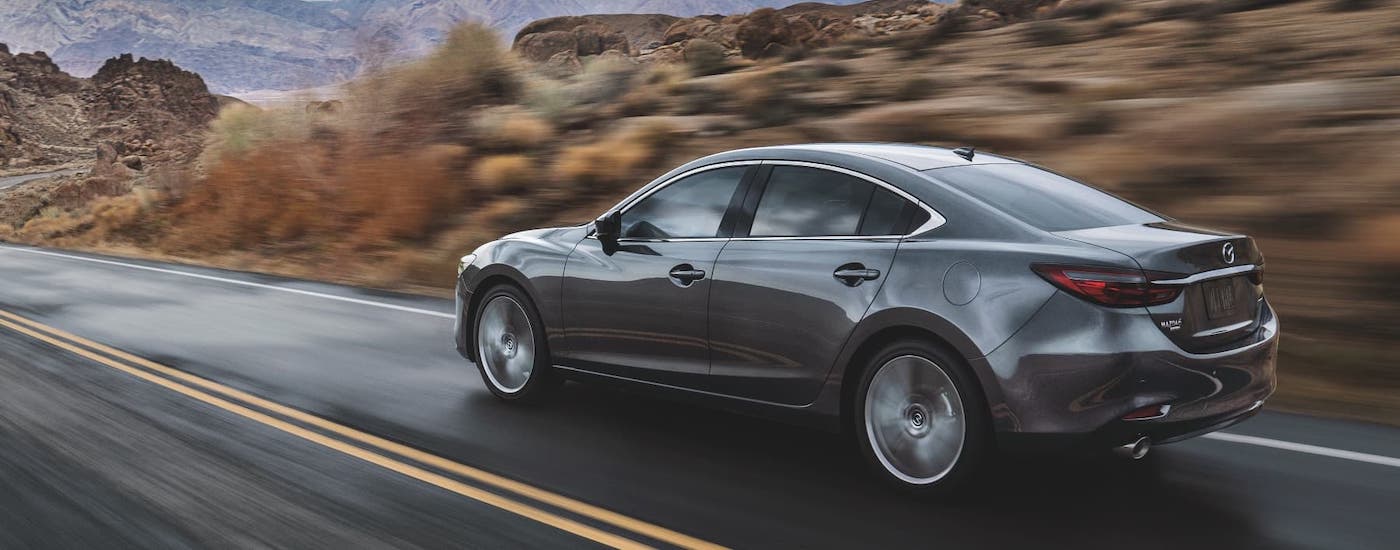 A gray 2021 Mazda6 is driving on a rocky mountain highway.