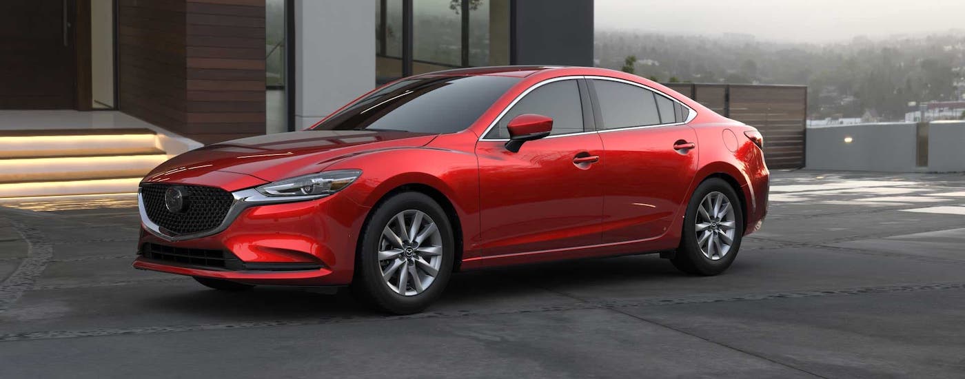 A red 2020 Mazda6 is parked in front of a modern home.
