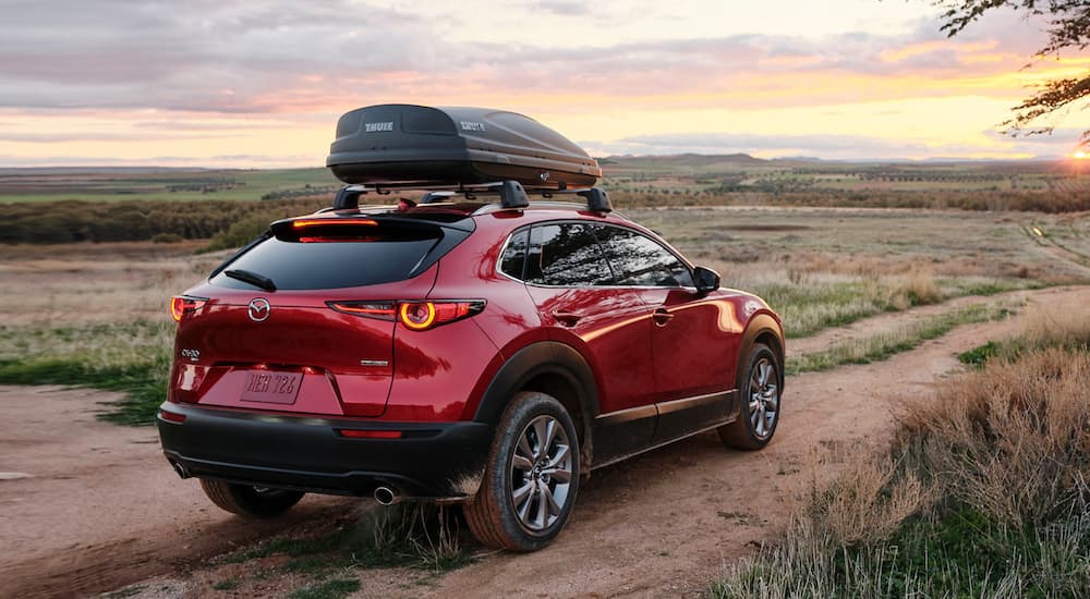 A red 2021 Mazda CX-30 is parked on a desert road at sunset.