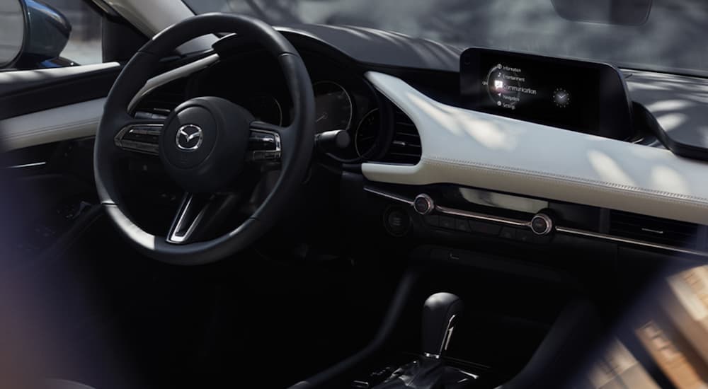 The interior of a 2021 Mazda3 shows the steering wheel and infotainment screen.