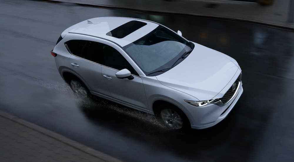 A white 2022 Mazda CX-5 is shown from a high angle driving down a wet road after visiting a Atascocita Mazda dealer.
