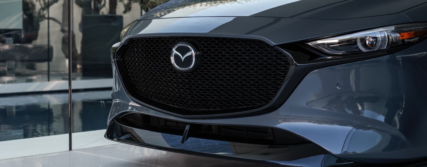 The front end of a grey 2021 Mazda 3 Hatchback from a Mazda dealer is shown in closeup.