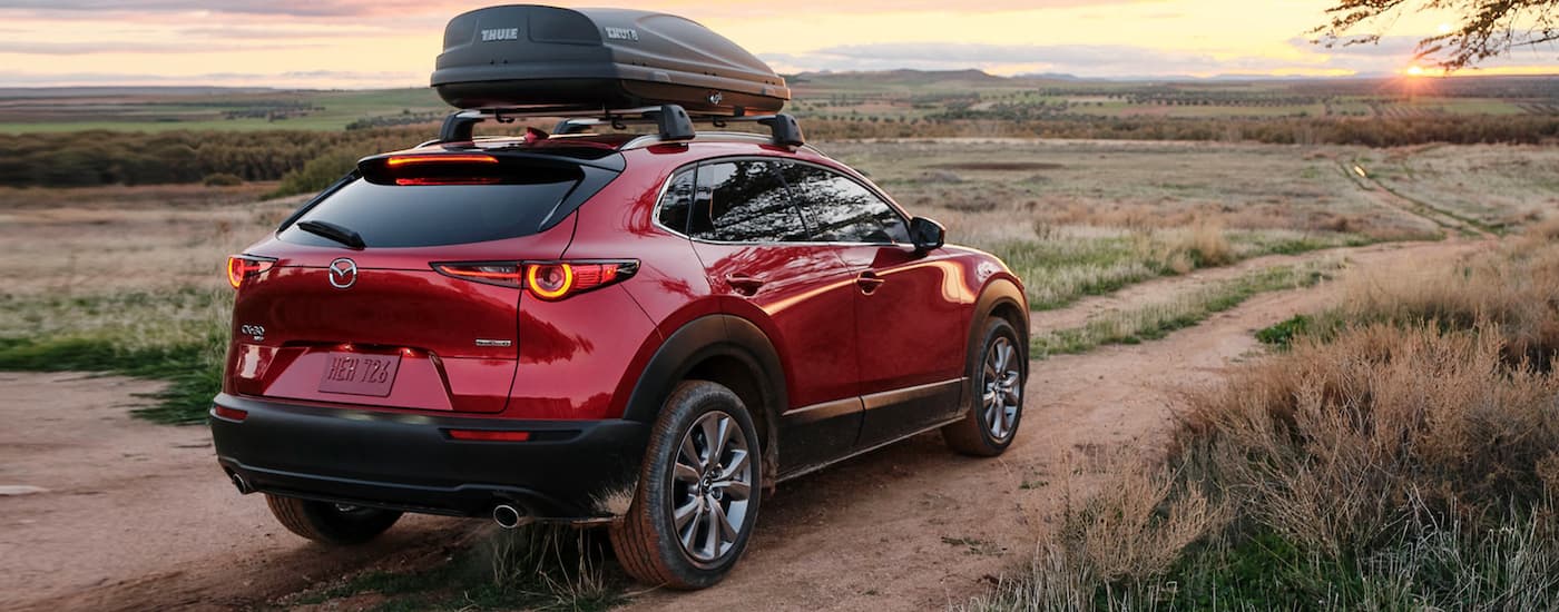 A red 2021 Mazda CX-30 is shown from the rear on a dirt path in the desert.