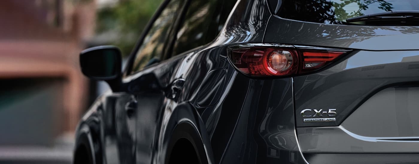 A close up shows the rear badge and taillight on a dark grey 2021 Mazda CX-5.