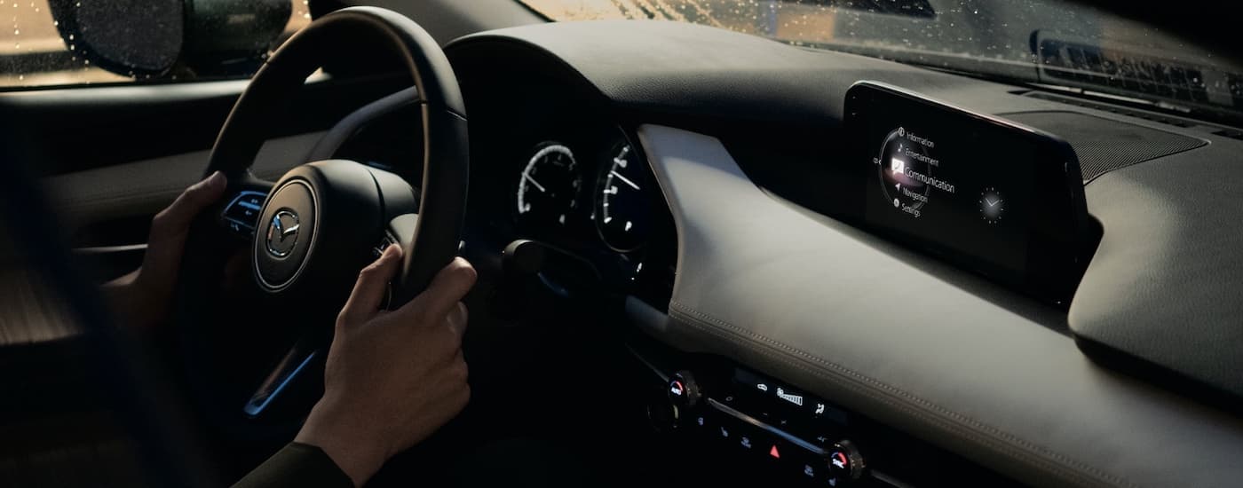 A close up shows the infotainment screen and steering wheel in a 2021 Mazda3 sedan.
