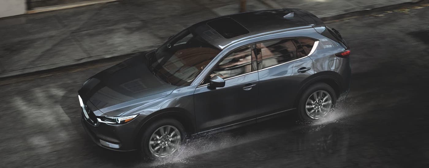 A gray 2021 Mazda CX-5 is shown from a high angle while driving in the rain.